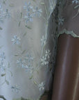 close up detail, glossy pale blue and green eyelet embroidery covering sheer organza of jacket topper