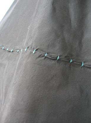 close up detail of turquoise stitch accents on black taffeta skirt