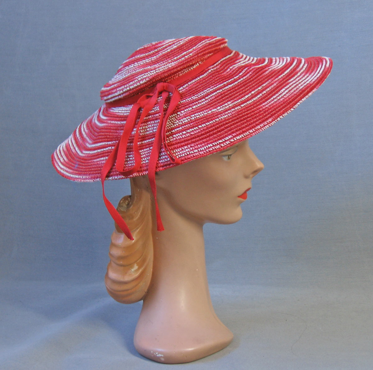 A vintage red and white ombre woven sun hat with red ribbon ties