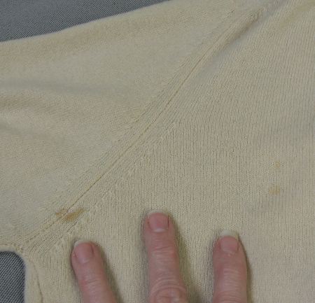 close up of small stain on left side of sweater back near underarm