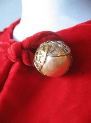 close up detail, decorative metallic ball button at neck of 40s red velvet coat