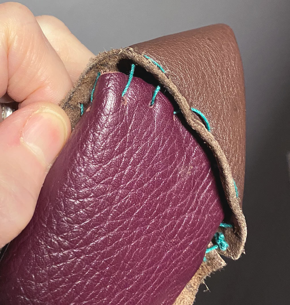 close up view, hand stitching nothing matches leather bag