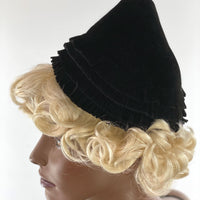 other side of black pixie hat showing decorative flat fringe and tassel at peak