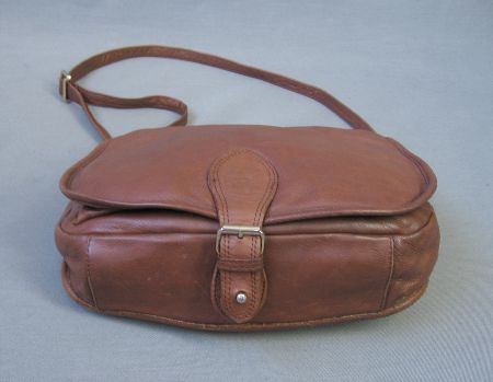 bottom view of leather bag, showing adjustable magnetized buckle closure